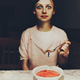 Woman eating soup with frightened expression